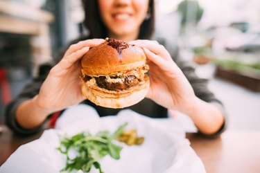 A woman eating an iron-rich beef burger outdoors