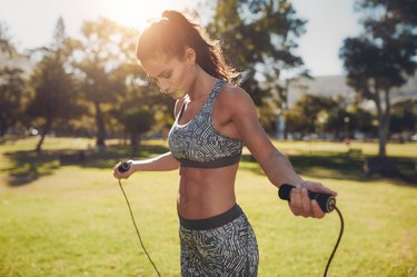 Fit young woman with jump rope in a park