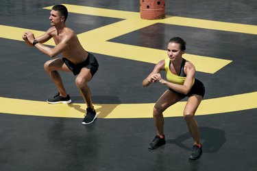 Sport people exercising, doing squat exercise workout outdoors