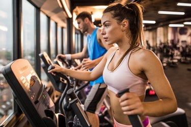 Determined woman exercising on a cross trainer in a gym