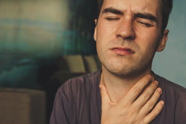 Man with a sore throat holding his neck in pain