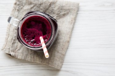 Glass jar of beetroot smoothie, top view. White wooden background. From above, overhead, flat lay. Copy space.