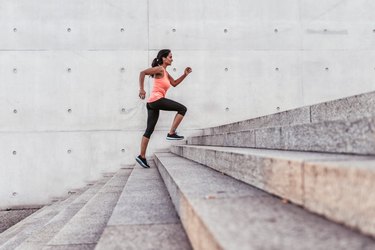 person in a bright pink shirt and black leggings running up large outdoor concrete stairway in Berlin