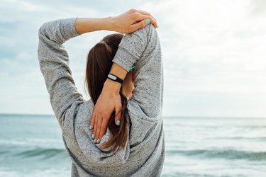 Girl in sportswear stretches the triceps in the morning