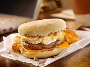 Sausage and Egg Breakfast Sandwich recipe on parchment paper on desk.