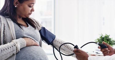 A pregnant woman getting her blood pressure taken by a doctor