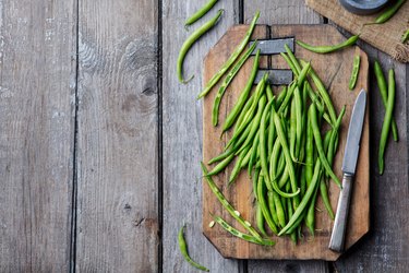 Green beans on wooden cutting board. Top view