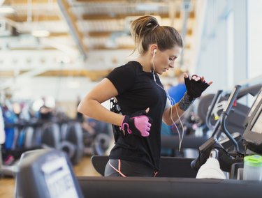 Woman running on treadmill at gym with headphones