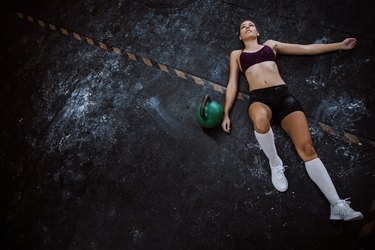 Tired Young Woman Lying Down In Gym