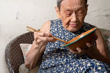 90年的健康的老妇raybet投注人吃午饭,前视图。