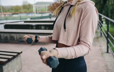 Girl training with dumbbells outdoors