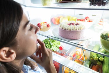 Young Woman Looking At Food In Refrigerator