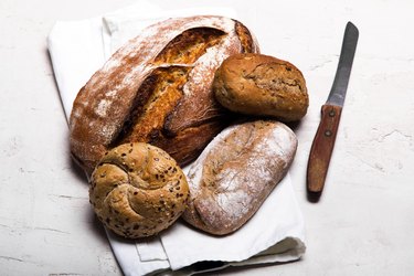 Tasty dark bread and buns  on white background, copy space. Bakery products, wholemeal bread and brown whole wheat buns