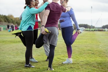 Competitors stretching legs together in park