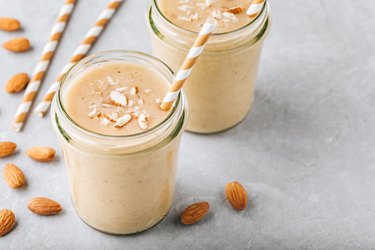 Banana almond smoothie with cinnamon and oat flakes and coconut milk in glass jars