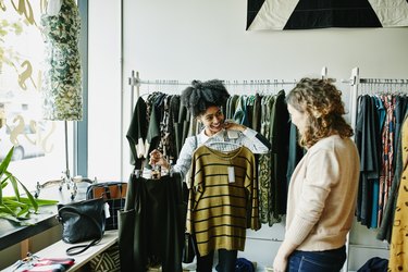 Smiling woman showing shop owner clothing options