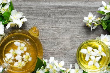 Cup of green herbal tea with jasmine flowers and teapot