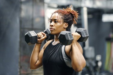 Fit, young African American woman working out with hand weights in a fitness gym.