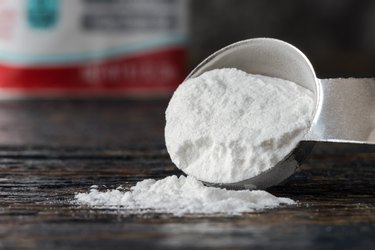 Close-Up Of Baking Soda Spilled From Measuring Spoon On Table