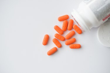 Orange pills cascading out of white bottle view from top