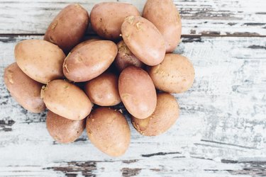 Тew potatoes on vintage wooden table top view