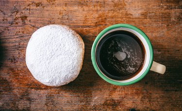 Coffee and krapfen with powder sugar, two, top view and isolated, wooden background.