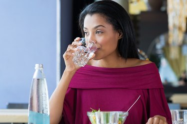 A woman sitting at a table and drinking water before eating lunch