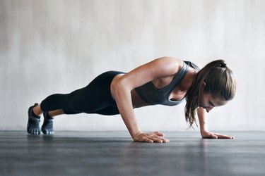 woman doing a push up on a a concrete floor