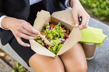 Businesswoman having lunch outdoors, partial view