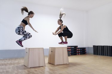 Athletes doing box jumps in the gym to demonstrate ways to build cardiovascular endurance.