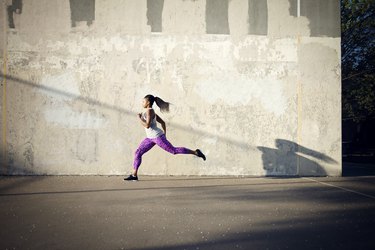 Woman jogging on street by wall