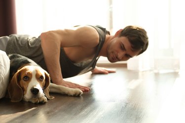 Man doing push-ups at home in his bedroom with his dog