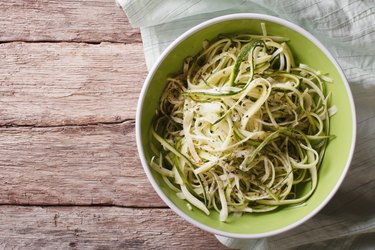 Useful raw zucchini pasta in a bowl closeup top view