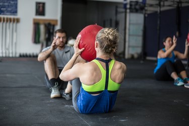 Adults doing ab workouts together with a medicine ball