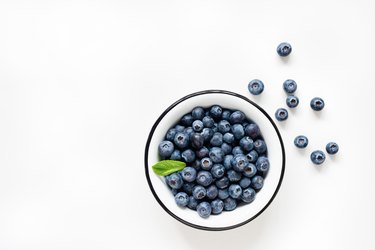 Fresh blueberries in bowl on white background
