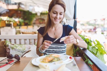 woman at an outdoor restaurant eating seafood, as an example of a natural remedy for fibroids