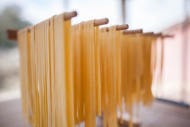 drying homemade pasta strings on wooden sticks