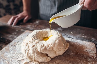 Adding olive oil to raw dough close-up