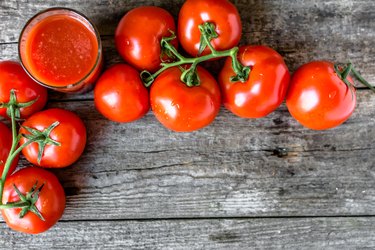 Glass of tomato juice on wooden table, flat lay from above