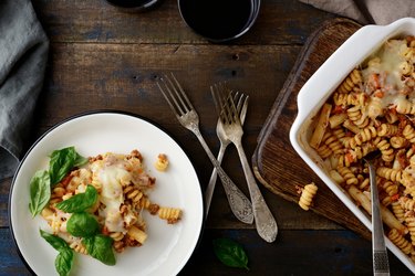 Pasta Bolognese with basil on plate and in baking dish