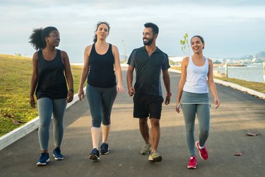 sporty friends walking on road against sky