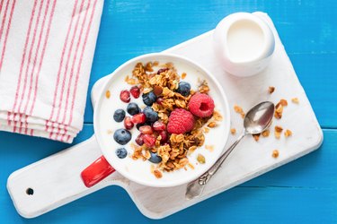 Yogurt with pomegranate seeds, fruits and breakfast cereals