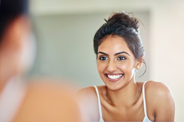 woman with healthy skin smiling in the mirror