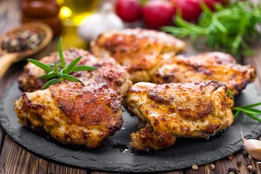 grilled chicken thighs on black plate with herbs