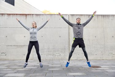 happy man and woman jumping outdoors