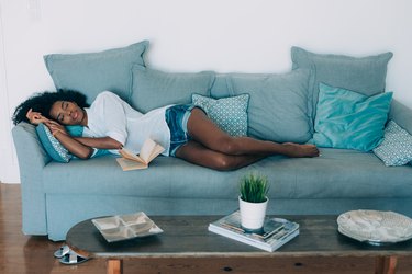 A young black woman taking a nap on a blue sofa