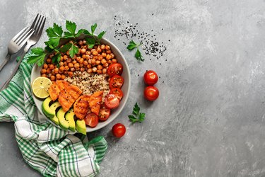 A bowl of healthy salad, fried chickpeas, fried sweet potatoes, avocado, quinoa, tomatoes and greens. Vegan and vegetarian dinner or lunch. Top view, flat lay.