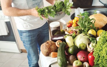 Assorted fruits and vegetables on a wooden table in a home kitchen, including potato juice for acid reflux