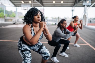 Three people doing squats as part of an outdoor HIIT workout