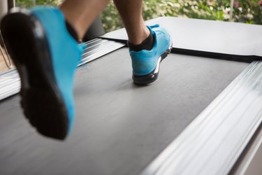 Runner's blue sneakers on treadmill doing cardio for weight loss